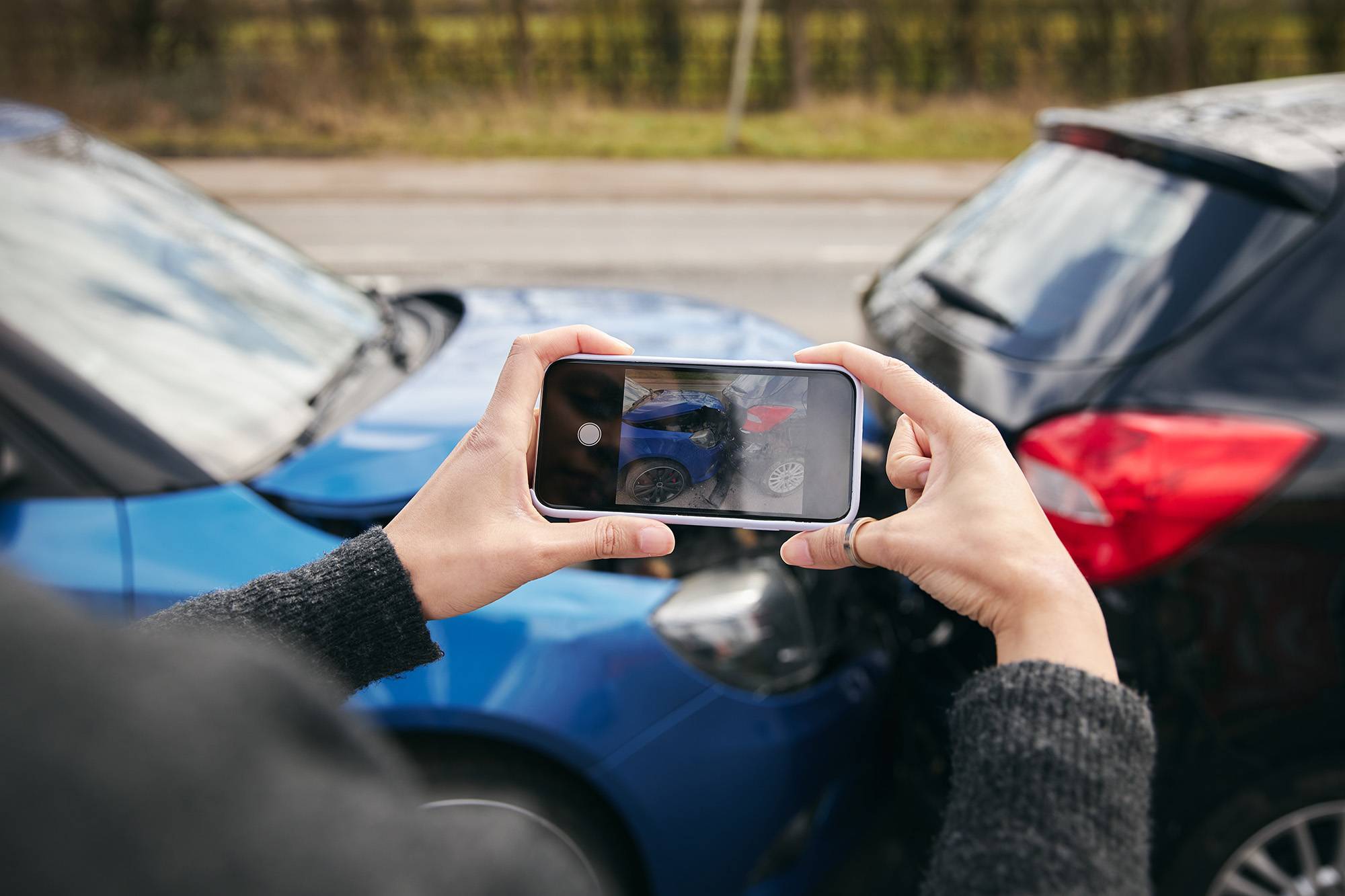 Person using a smartphone to photograph car accident damage.